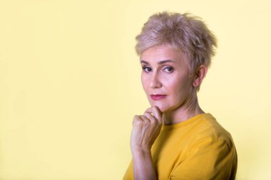 şık yaşlı kadın ile sarı bir arka plan üzerinde ciddi bir yüz ile bir kısa saç modeli