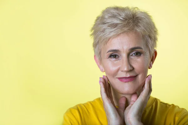 stylish elderly woman with a short hairstyle on a yellow background