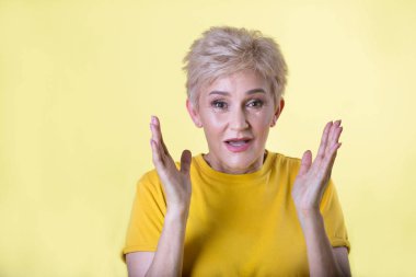 korkmuş bir ifade ile sarı bir arka plan üzerinde kısa bir saç modeli ile güzel şık kadın