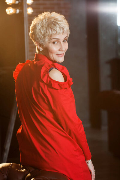 beautiful elderly woman with a short hairstyle in a red dress in the interior