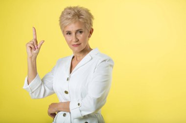 Yetişkin şık kadın doktor el hareketi ile sarı zemin üzerine beyaz önlük içinde