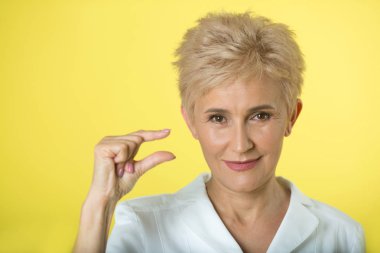 Yetişkin şık kadın doktor el hareketi ile sarı zemin üzerine beyaz önlük içinde