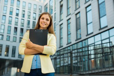 Bina arka plan sarı ceketli güzel genç kız ile bir klasör içinde belgelerin eller