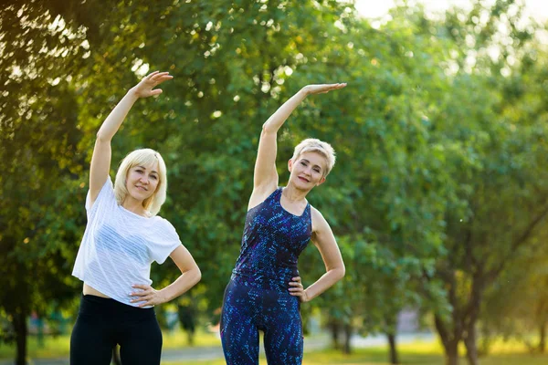 iki şık güzel kadın parkta yaz aylarında spor vardır