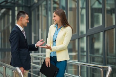 iş belgelerinin elinde bir klasörle bir adamla tartışırken bir ceketi giyen genç güzel kız