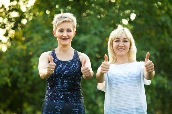 在公园里做运动的两个女人用手做手势 — 图库照片