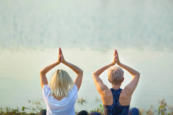 夏天在河边做瑜伽的两个年长的妇女 — 图库照片
