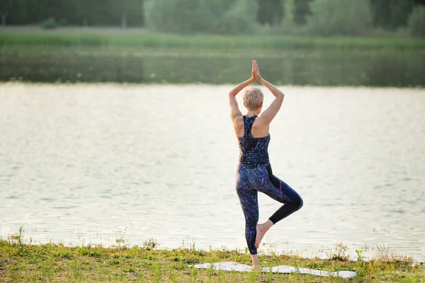 Yaşlı kadın yaz aylarında lotus pozisyonu Nehri yakınında yoga yapıyor