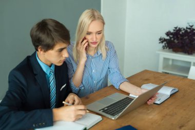 güzel genç girişimciler adam ve bir dizüstü bilgisayar ile masada ofiste oturan kadın