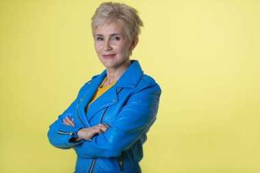 içinde mavi bir ceket ve sarı bir arka plan üzerinde bir kısa saç modeli ile yaşta şık kadın