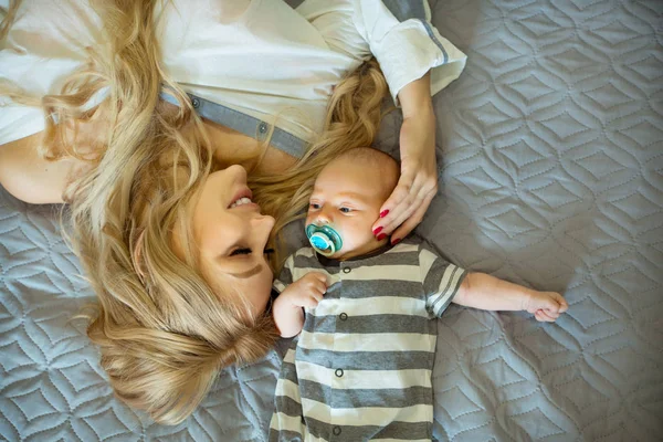 自宅のベッドで小さな子供と一緒に横になっている美しい若い女性 — ストック写真