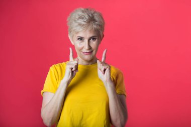 bir hareketi el ile kırmızı bir arka plan üzerinde sarı bir tişört kısa bir saç kesimi ile yaşta şık kadın