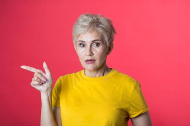 bir hareketi el ile kırmızı bir arka plan üzerinde sarı bir tişört kısa bir saç kesimi ile yaşta şık kadın