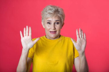 bir hareketi el ile kırmızı bir arka plan üzerinde sarı bir tişört kısa bir saç kesimi ile yaşta şık kadın