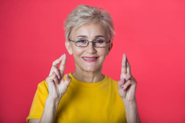 kısa saç kesimi ve bir jest bir kırmızı zemin üzerine sarı bir tişört giyen gözlük el ile şık yaşlı kadın