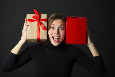 elinde siyah bir arka plan üzerinde bir hediye ile güzel genç kız