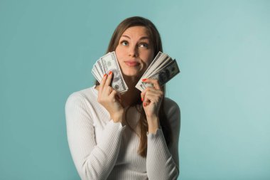 güzel genç kız mavi bir arka plan üzerinde elinde dolarla