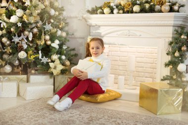 güzel kız beyaz kazaklı Noel ağacının yanında oturur bir hediye ile el