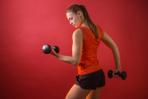 Onun Elinde Dumbbells Ile Şort Yelek Kırmızı Bir Arka Plan — Stok fotoğraf