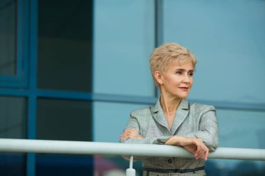 Yaz aylarında Mimari camlar arka planı gri elbiseli kısa bir saç kesimi ile şık modern kadın