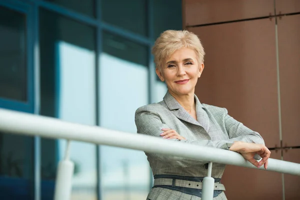 stylish modern woman with a short haircut in a gray suit against the background of the building in summer