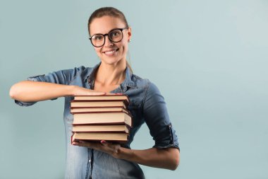 güzel genç kız gözlüklü kitaplar onun elinde tutan bir mavi arka planı