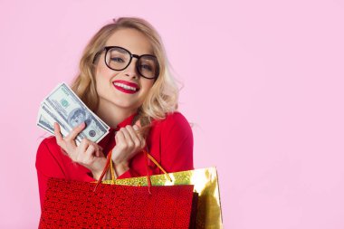 güzel genç kız ile dolar ve paketleri ellerindeki pembe bir arka plan üzerinde kırmızı gömlekli