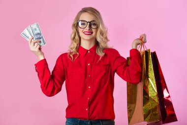 güzel genç kız ile dolar ve paketleri ellerindeki pembe bir arka plan üzerinde kırmızı gömlekli