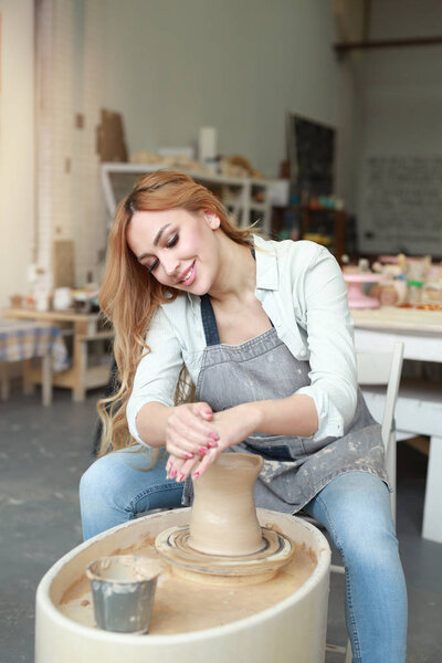 beautiful young girl makes a jug of clay in a pottery workshop
