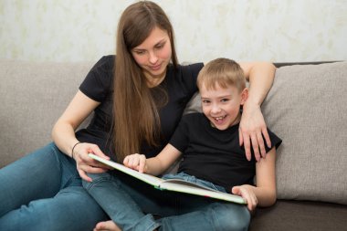 güzel genç aile anne ve oğlu evde bir kitap okumak