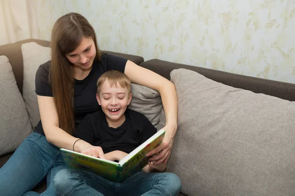 beautiful young family mom and son read a book at home