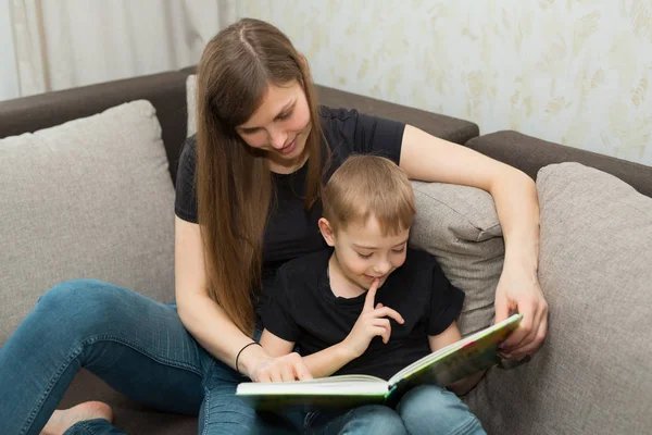 beautiful young family mom and son read a book at home