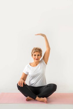 Beyaz bir arka plan üzerinde yoga yaparken şık yaşlı kadın