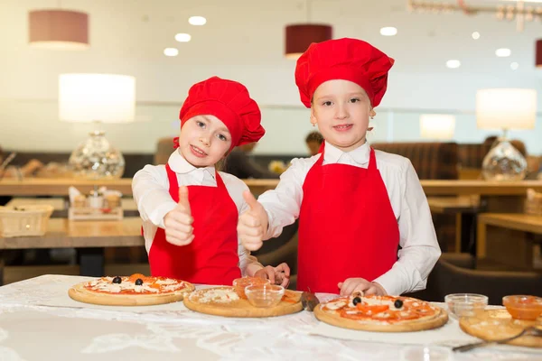 two beautiful cook girls in white shirts and red aprons in a restaurant with a gesture of hands