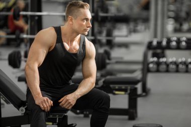 spor salonunda kasları ile iyi durumda yakışıklı adam