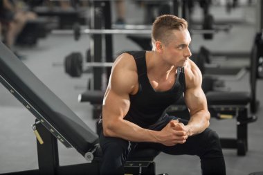 spor salonunda kasları ile iyi durumda yakışıklı adam