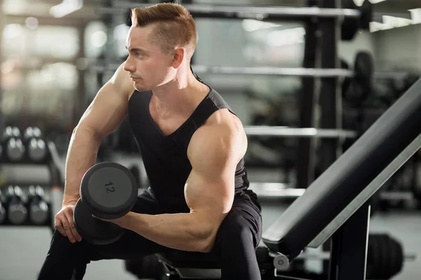英俊的男人在良好的形状与肌肉在健身房锻炼与哑铃 — 图库照片