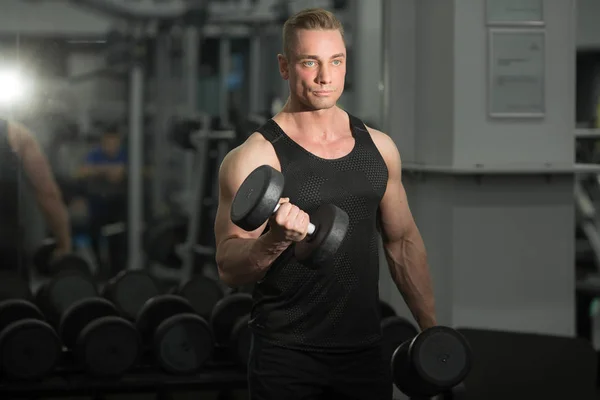 英俊的男人在良好的形状与肌肉在健身房锻炼与哑铃 — 图库照片