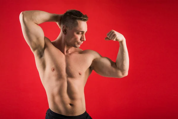 Kjekk Ung Mann Atletisk Form Rød Bakgrunn Viser Musklene Sine – stockfoto