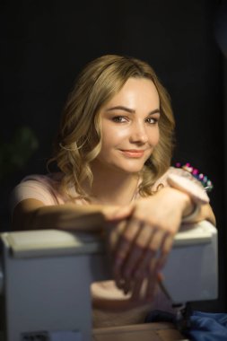 güzel genç kız iş yerinde gece bir dikiş makinesi üzerinde bir elbise diker