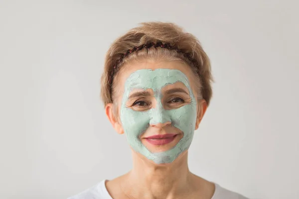 beautiful elderly woman with a wellness cream face mask