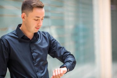 siyah gömlekli yakışıklı genç adam kapalı onun saat bakar