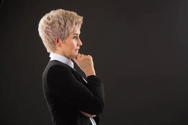 stylish elderly woman with a short haircut in a black suit on a black background