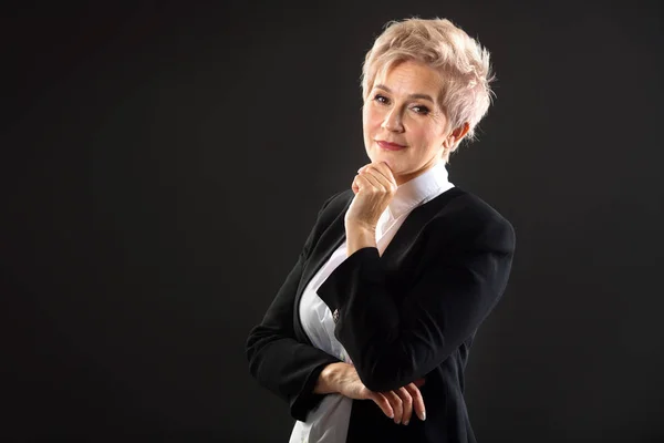 siyah bir arka plan üzerinde siyah takım elbise kısa bir saç kesimi ile şık yaşlı kadın