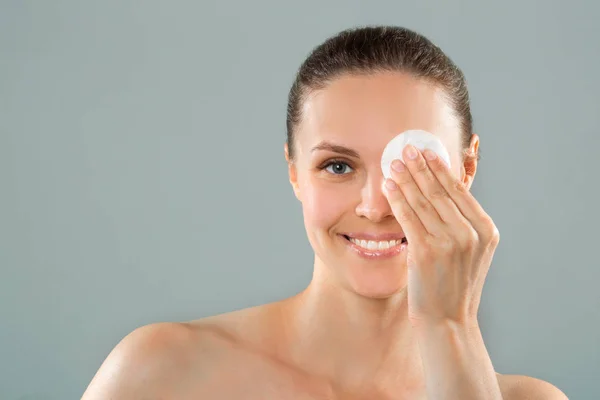 beautiful young woman cleansing facial skin with a napkin