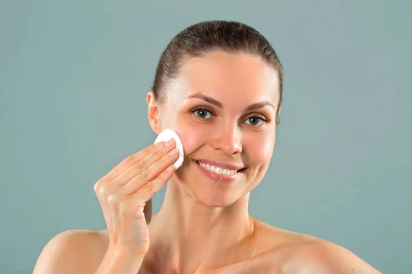 beautiful young woman cleansing facial skin with a napkin