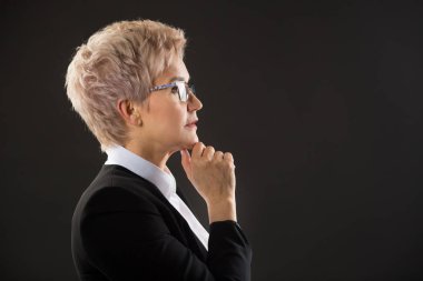 Gözlükşık yaşlı kadın ve yüzünde ifade ile siyah bir arka plan üzerinde siyah bir ceket