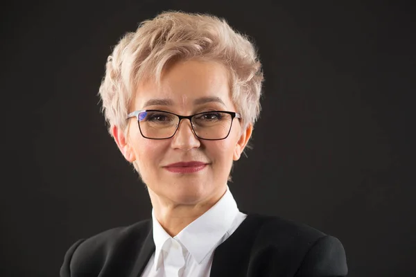 stylish elderly woman in glasses and black jacket on a black background