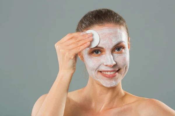 beautiful young woman with a cleansing napkin in her hand and cream mask on her face