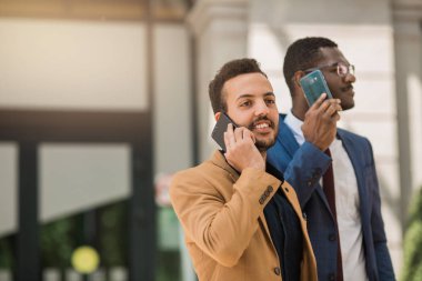 takım elbiseli iki adam telefonda konuşuyor